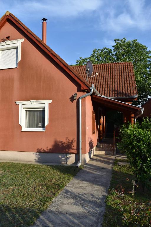 a red house with a pathway next to it at Bozóki Apartman in Kiskunmajsa