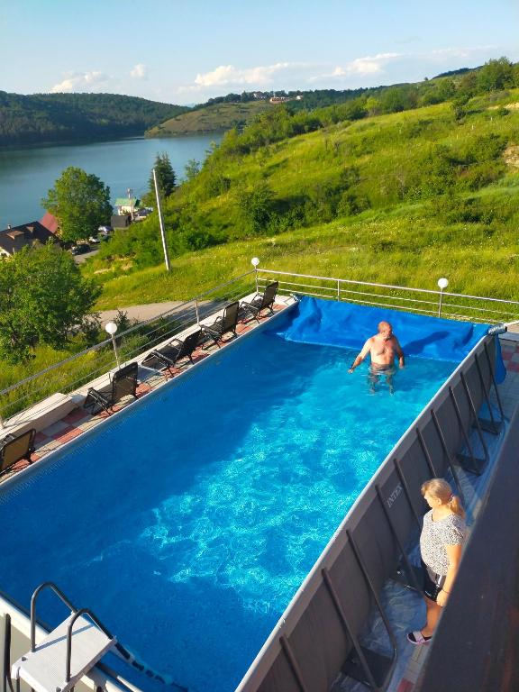a man and a woman standing in a swimming pool at Pensiunea Casa Vio in Cinciş