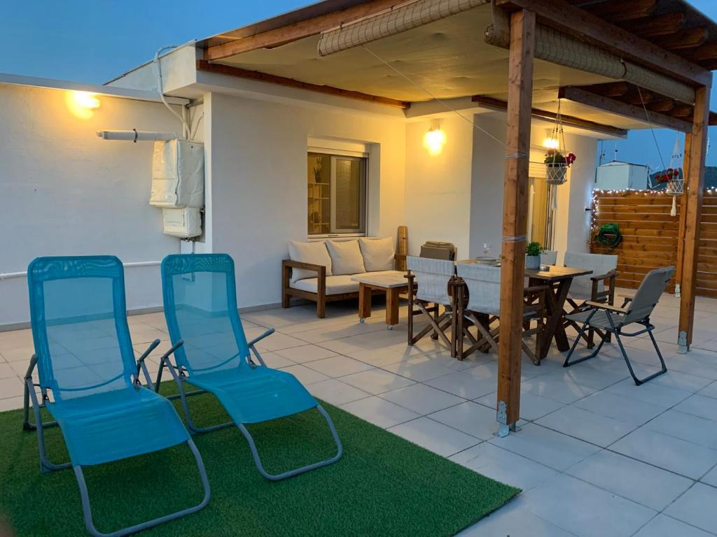 a patio with blue chairs and a table and a table at Milla Terrace Apartment Volos in Volos