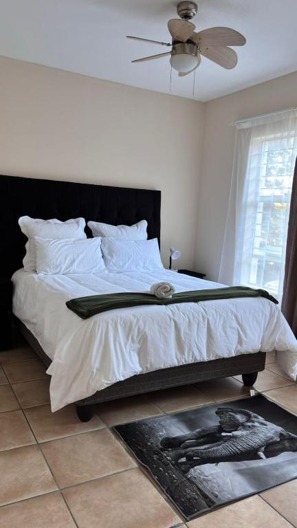 a bedroom with a bed with white sheets and a fan at Success Guesthouse in Nelspruit