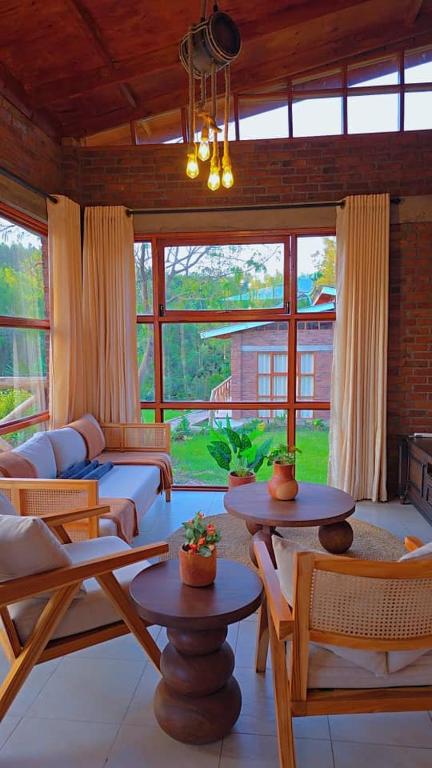 ein Wohnzimmer mit Sofa, Tischen und Fenstern in der Unterkunft Daima Escape in Usa River