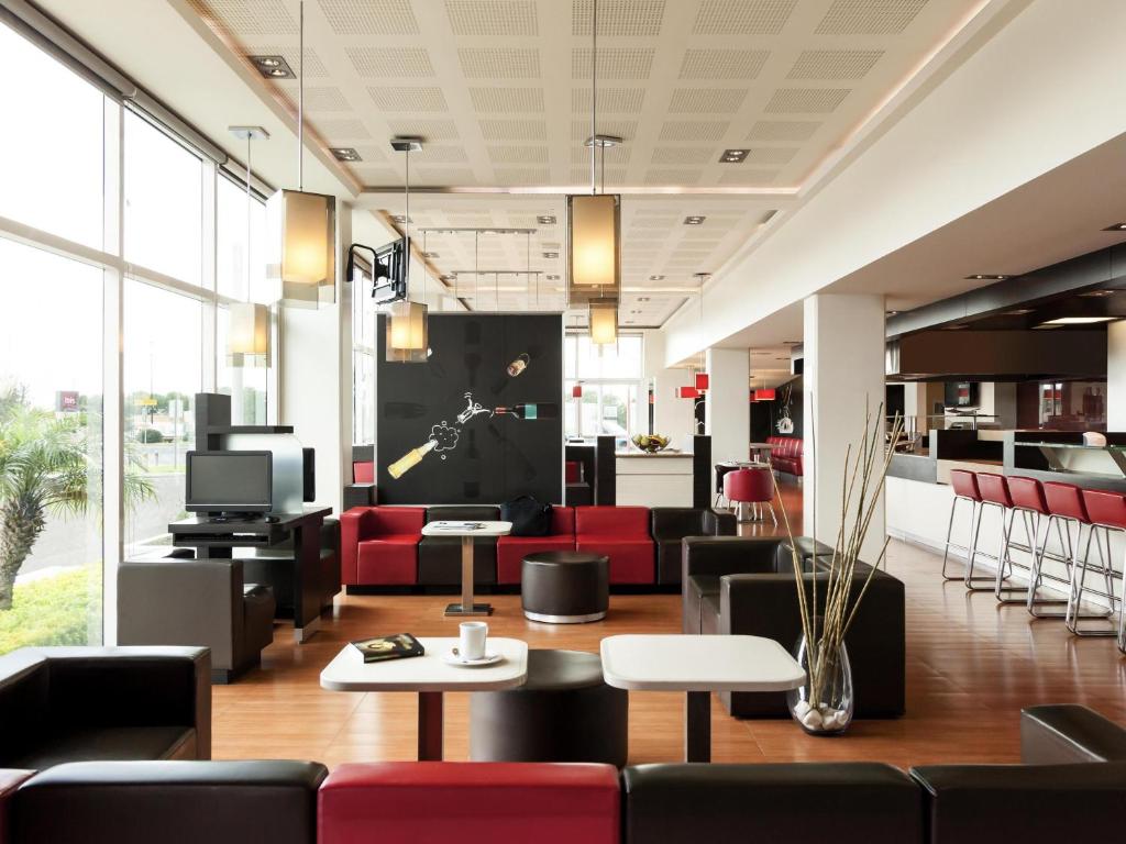 eine Lobby mit roten und schwarzen Stühlen und einem Fernseher in der Unterkunft Ibis Aguascalientes Norte in Aguascalientes