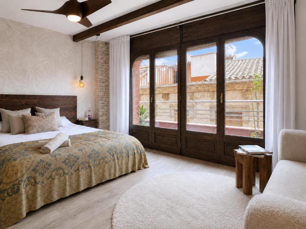 a bedroom with a bed and a chair and a window at Apartamento Ca Blai de Brull en el centro de Tivissa in Tivissa