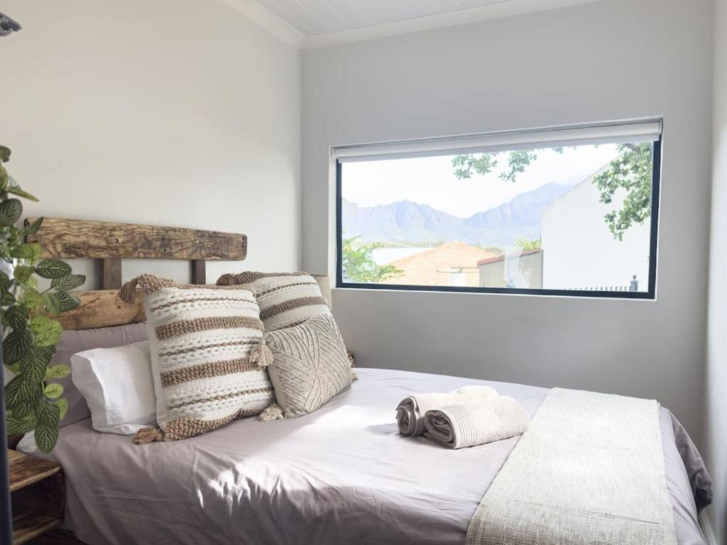 a bedroom with a bed with pillows and a window at Romantic Tulbagh Getaway in Tulbagh
