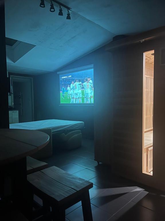 a dark room with a tv and a table and a bench at Suite avec Sauna 36m² in Niort