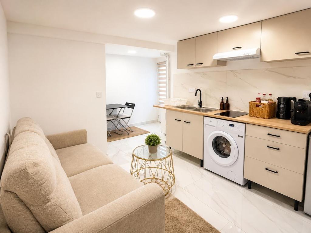 a living room with a couch and a washing machine at EDEN SUITE Escale proche de CDG in Tremblay-En-France