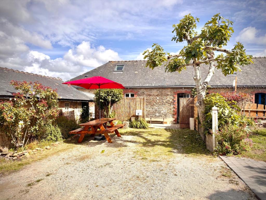 a picnic table with a red umbrella in front of a building at Maison Ty Bihan Sioul in Sarzeau
