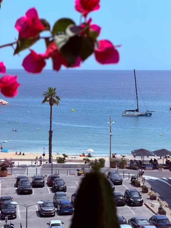 a parking lot with a beach and a boat in the water at T2 "Bohême" vue mer, centre ville tout à pied in Le Lavandou