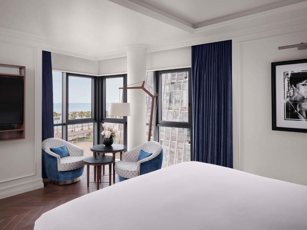 a bedroom with a bed and two chairs and a window at Sofitel Barcelona Skipper in Barcelona