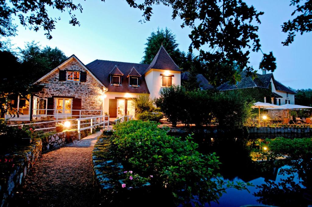 a house with a pond in front of it at night at Au Moulin de La Gorce in La Roche-lʼAbeille