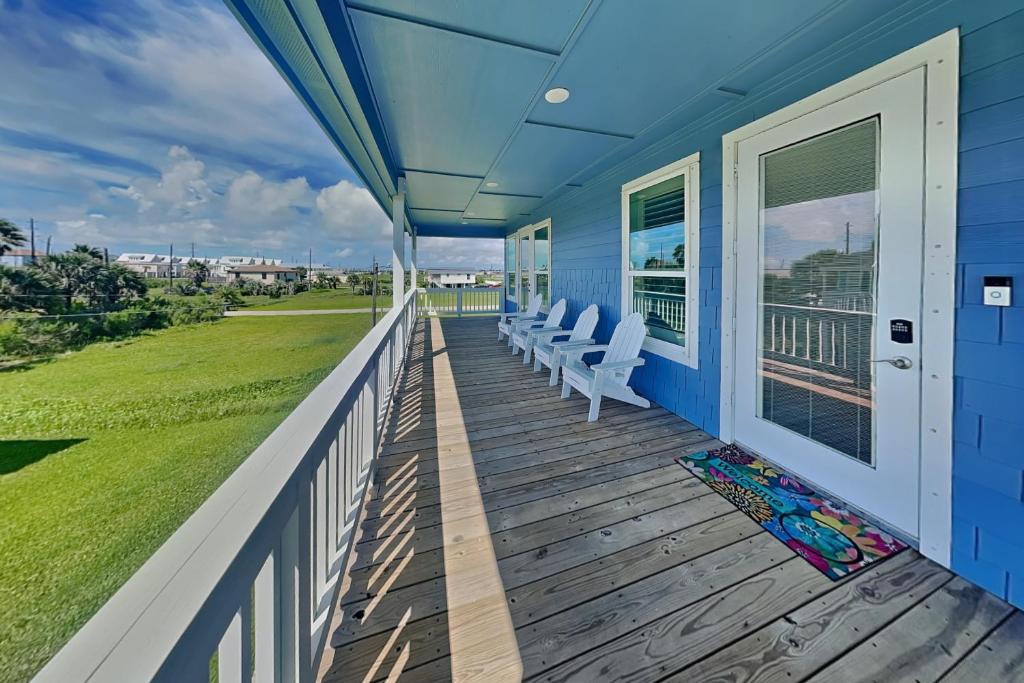 a porch with white chairs on a blue house at Tortuga Moon in Galveston