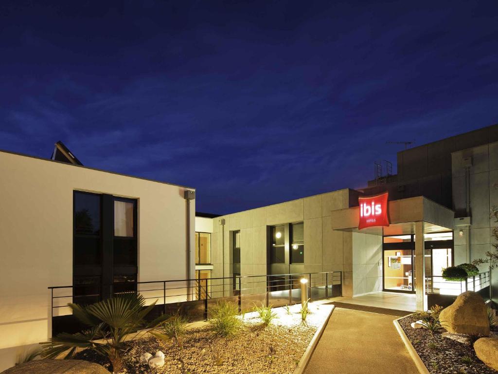 a building with a lit up exit sign in front of it at Hôtel ibis Guingamp Cœur de Bretagne in Ploumagoar