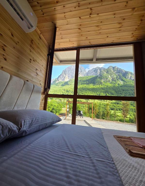 a bedroom with a bed with a view of a mountain at Visi Cabins Bogë in Bogë