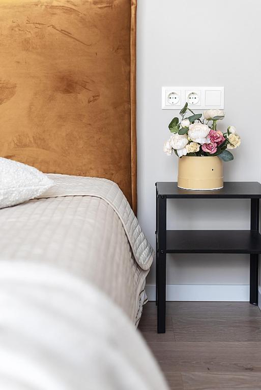a bedroom with a bed and a table with a vase of flowers at V39 New Apartment in Vilnius