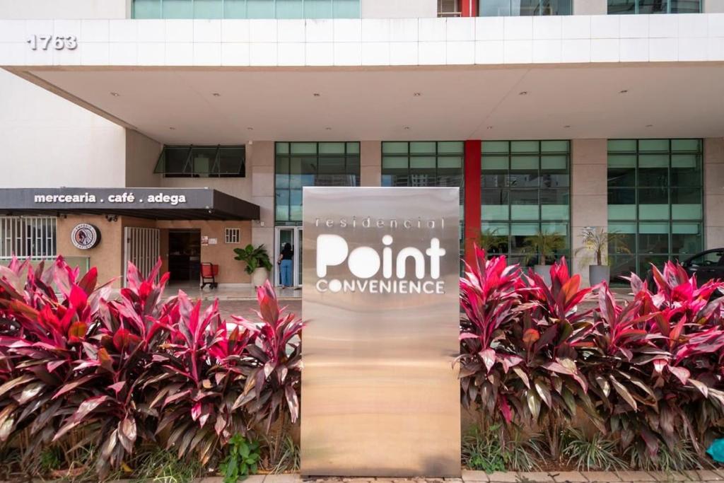 a sign in front of a building with plants at Point Convenience by Marzani Host in Goiânia