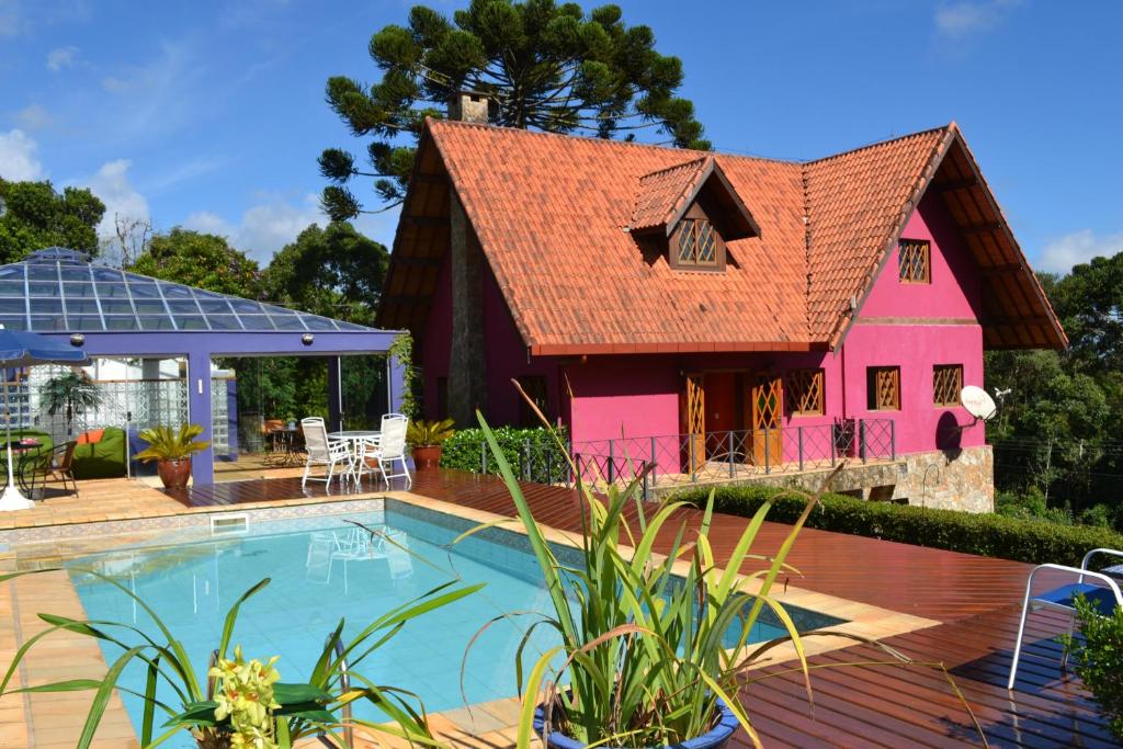 uma casa com piscina e uma casa cor-de-rosa em Pousada Ana Terra em Monte Verde