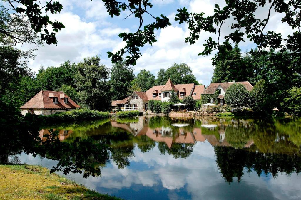 una fila de casas en un río con árboles en Au Moulin de La Gorce, en La Roche-lʼAbeille