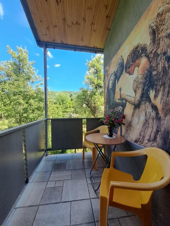 a balcony with a table and chairs and a mural at panorama lasuriashi in Lasuriashi