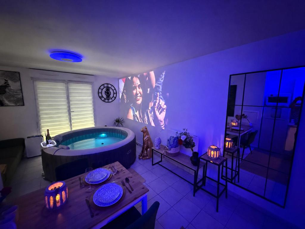 a room with a large tub in a room with purple lights at Suite Eden Spa, Appart'hôtel bien être , Patio de standing barbecue - TV XL CinéSport, Lit Q-Size, Wifi, P-Gratuit en Résidence in Avion