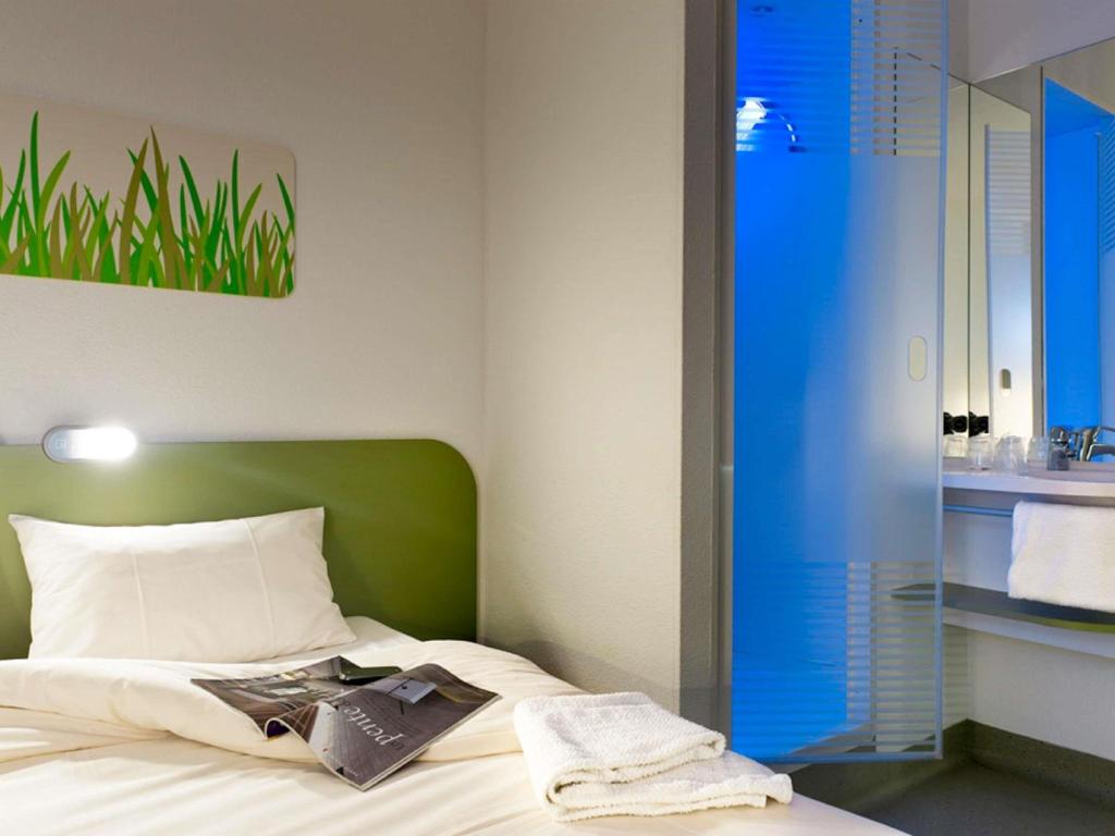 a bedroom with a bed with a green headboard and a sink at ibis budget Antwerpen Port in Antwerp