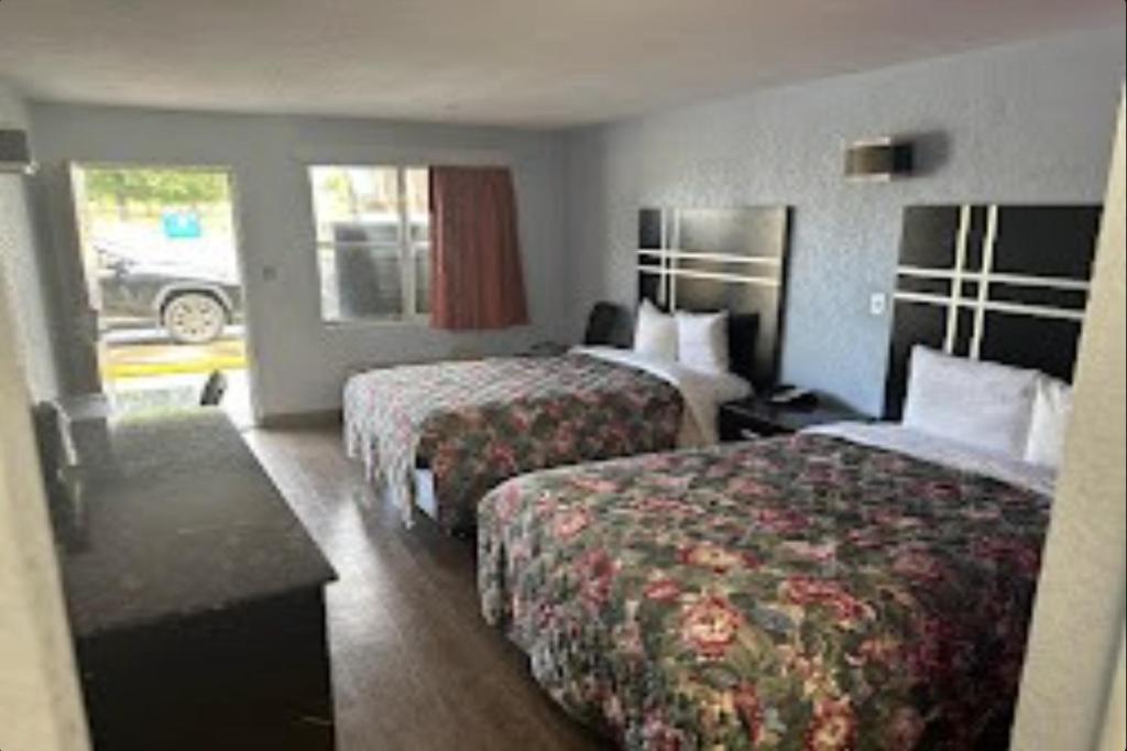 a hotel room with two beds and a table at Relax Inn Hotel in Birmingham