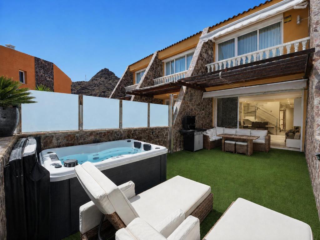 a backyard with a hot tub and lounge chairs at Villa Gisel in La Playa de Tauro
