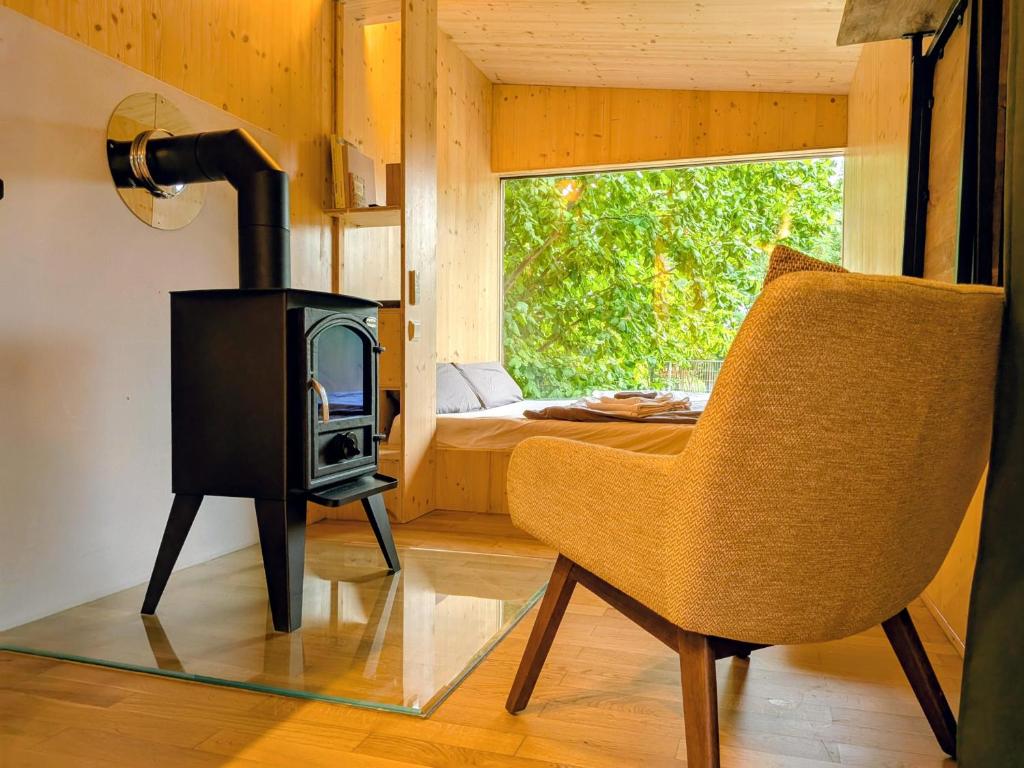 a room with a stove and a chair and a bed at Modernes Tiny House in historischem Ambiente in Neu Kaliß