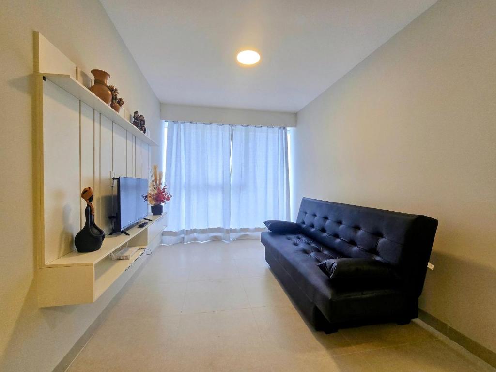 a living room with a black couch and a television at Life Center in Caruaru