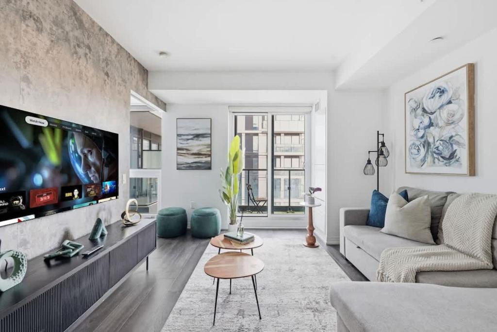 a living room with a couch and a flat screen tv at Charming 2BR downtown condo with private patio in Toronto