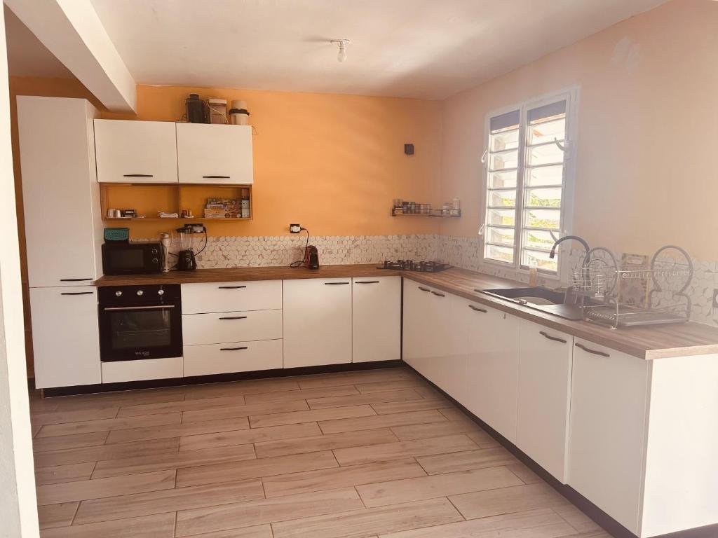 a large kitchen with white cabinets and a window at Cap Alizés in Petit-Canal