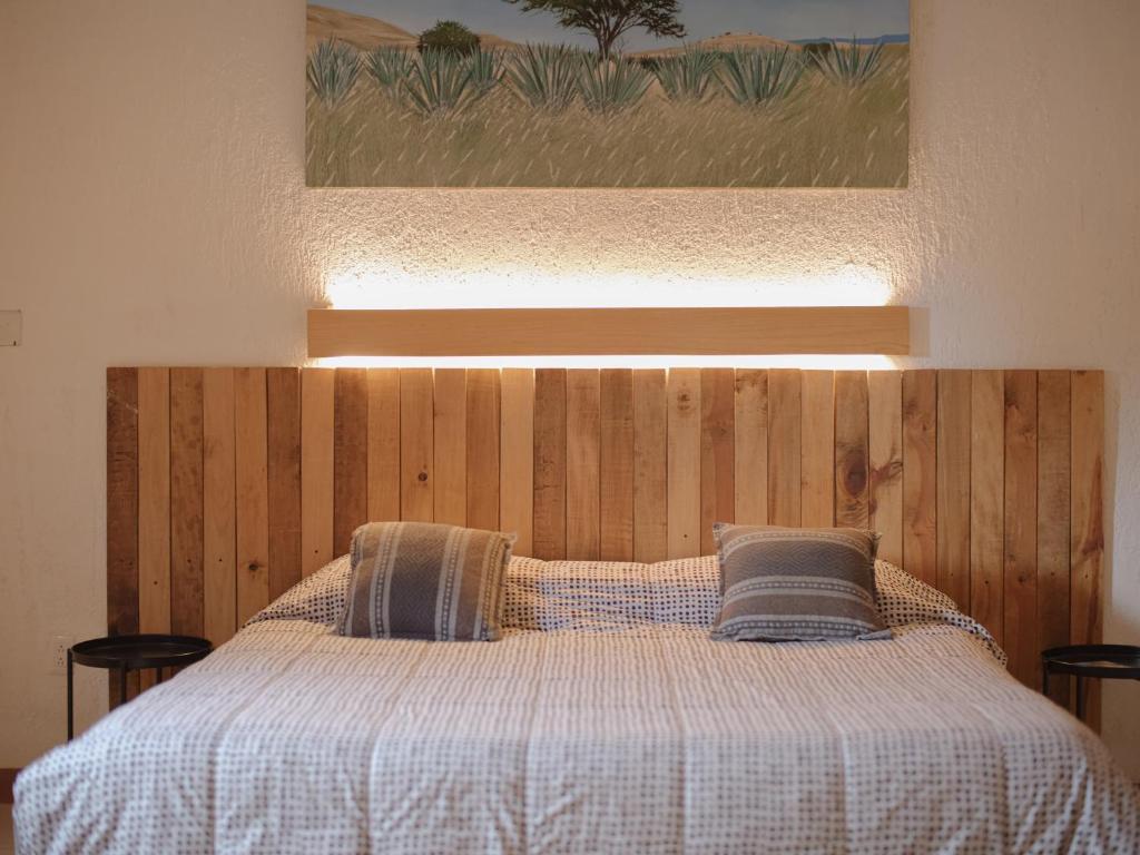a bed with a wooden head board with two pillows at Departamento Yotao in Oaxaca City