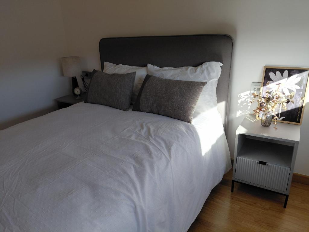a bedroom with a large white bed and a night stand at Brisas de Malpica in Malpica