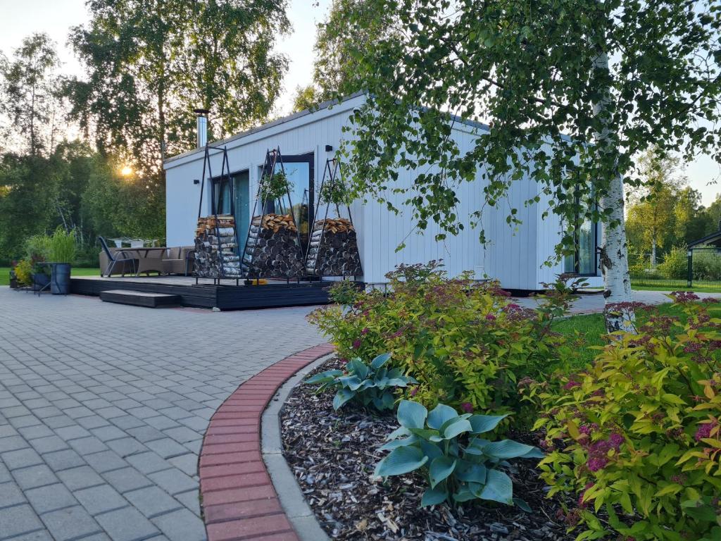 a white tiny house with a patio in a yard at Apšuciema Birzīši in Apšuciems
