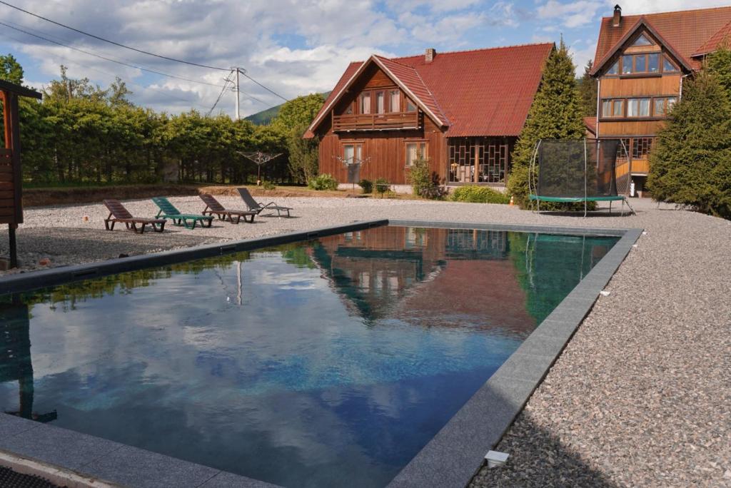 a swimming pool with two benches and a house at Gostynniy Dvir Raytshtoky in Vorokhta