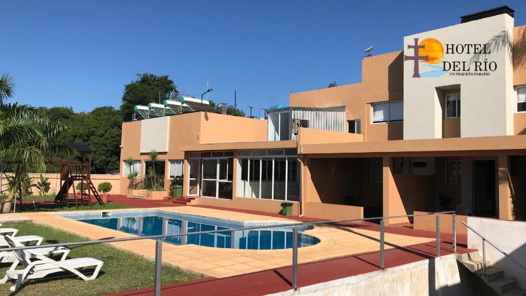 a villa with a swimming pool in front of a building at Hotel del Rio - La Cruz Corrientes in La Cruz