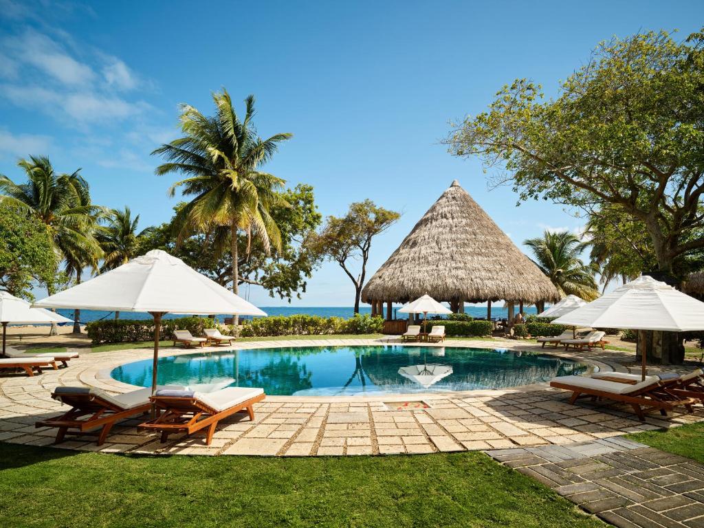 a pool at a resort with chairs and umbrellas at Turtle Inn by Francis Ford Coppola in Placencia