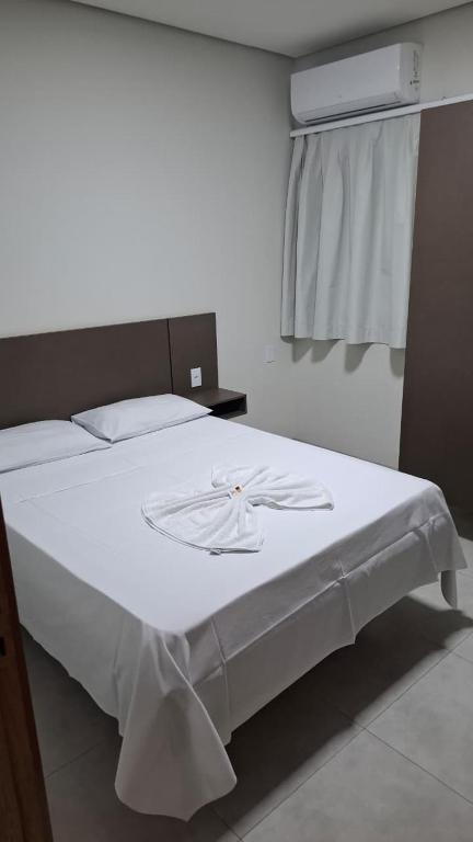 a bedroom with a bed with a white bedspread on it at Hotel Comodoro in Vilhena