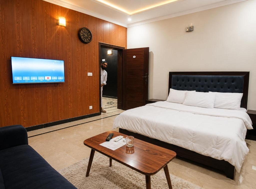 a bedroom with a bed and a couch and a tv at Opal Orchid House in Islamabad