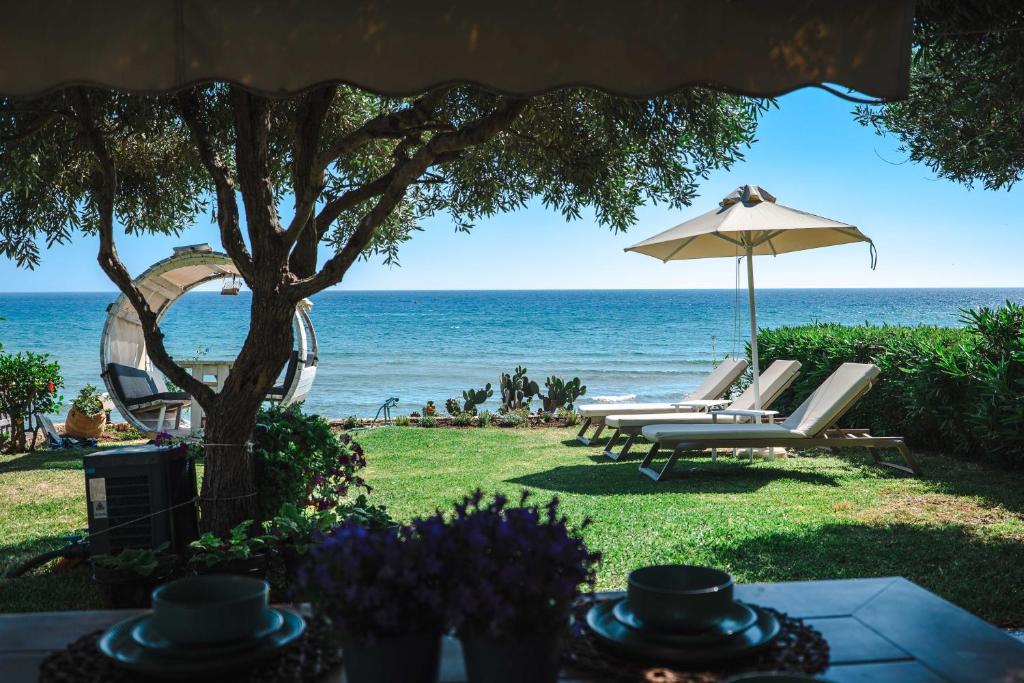 a group of chairs and an umbrella on the beach at Corfu Glyfada Beach Apartment 13 in Glyfada