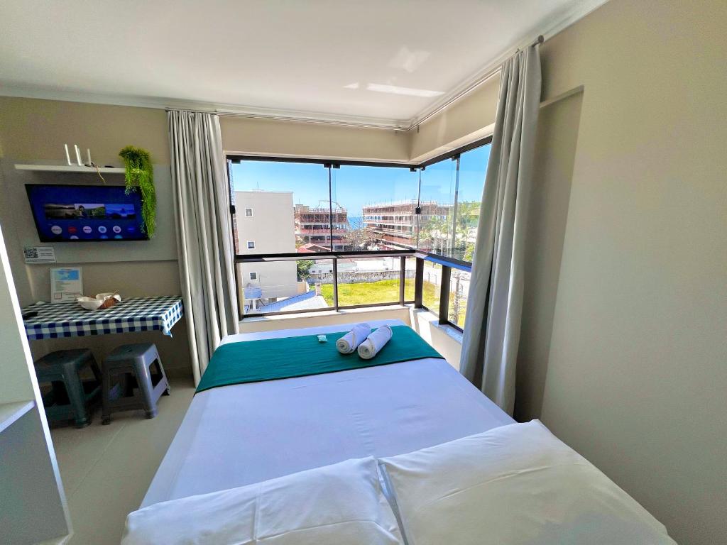 a bedroom with a bed and a large window at Bella Catarina Bombinhas in Bombinhas