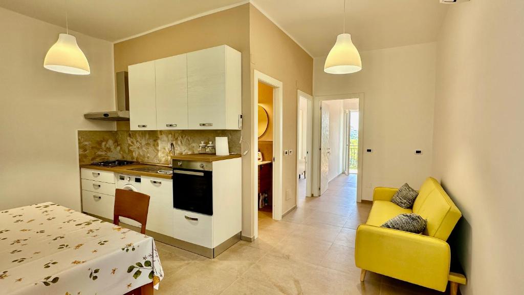 a kitchen and living room with a yellow couch and a table at Cilento HOME in Ogliastro Cilento