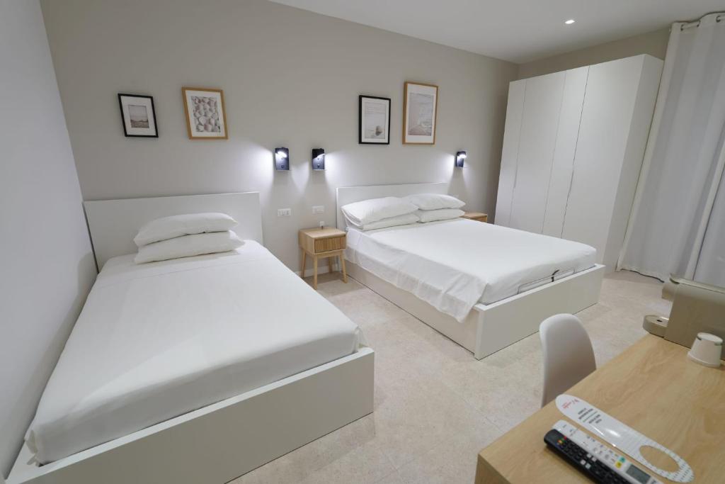 a bedroom with two beds and a table and a desk at ResidenzaMarèa in Scalea