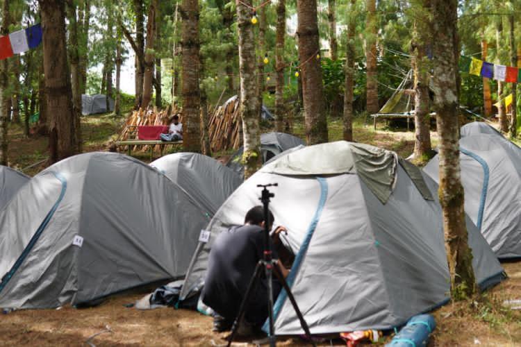 a man with a camera standing in a tent at Camp Wildnest Adventures Ziro in Ziro