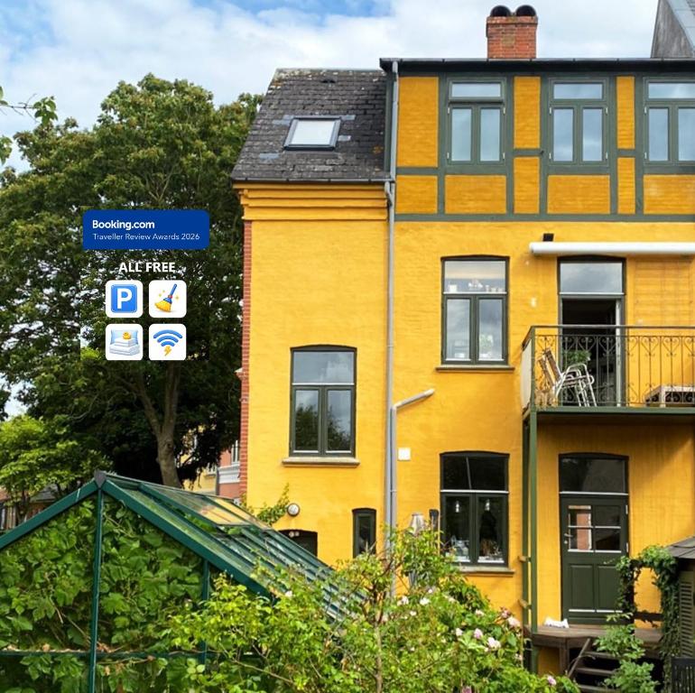 a yellow building with a blue street sign in front of it at Charming Heritage Townhouse in Odense