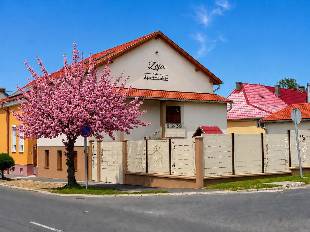 a pink flowering tree in front of a building at Zója Apartmanház in Nagykanizsa