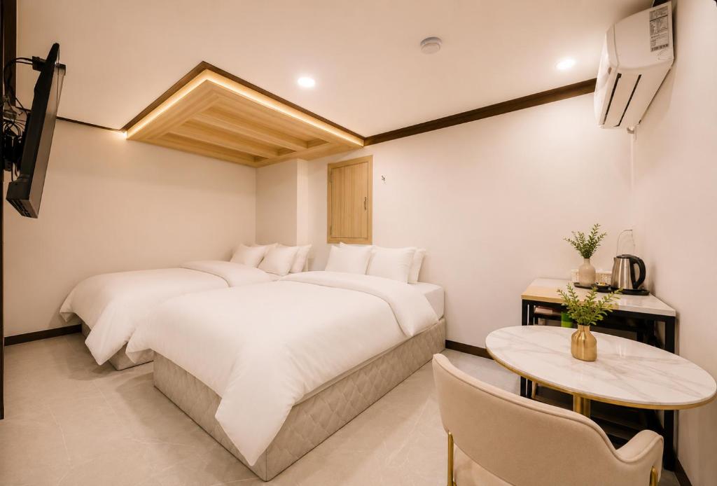 a hotel room with two beds and a table at Ramon Hotel in Seoul