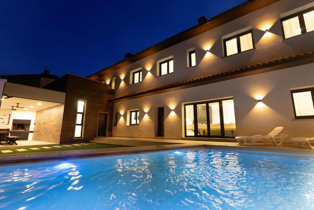 a swimming pool in front of a house at night at Alojamiento ENSUEÑOS in Ciudad-Rodrigo