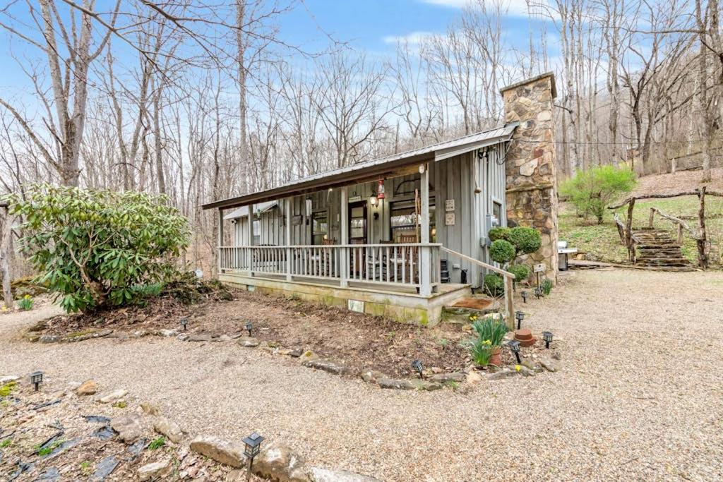 a small house with a porch and a stone building at Hidden Creek Cabin in Franklin