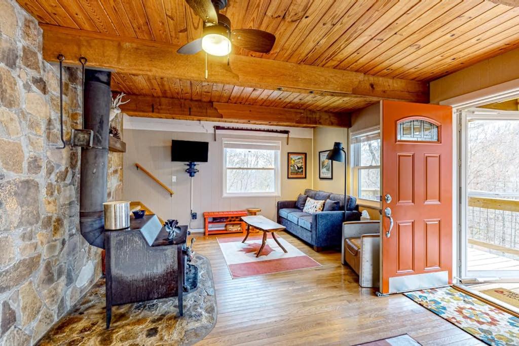a living room with a stone wall and a red door at Bryson Chalet in Bryson City