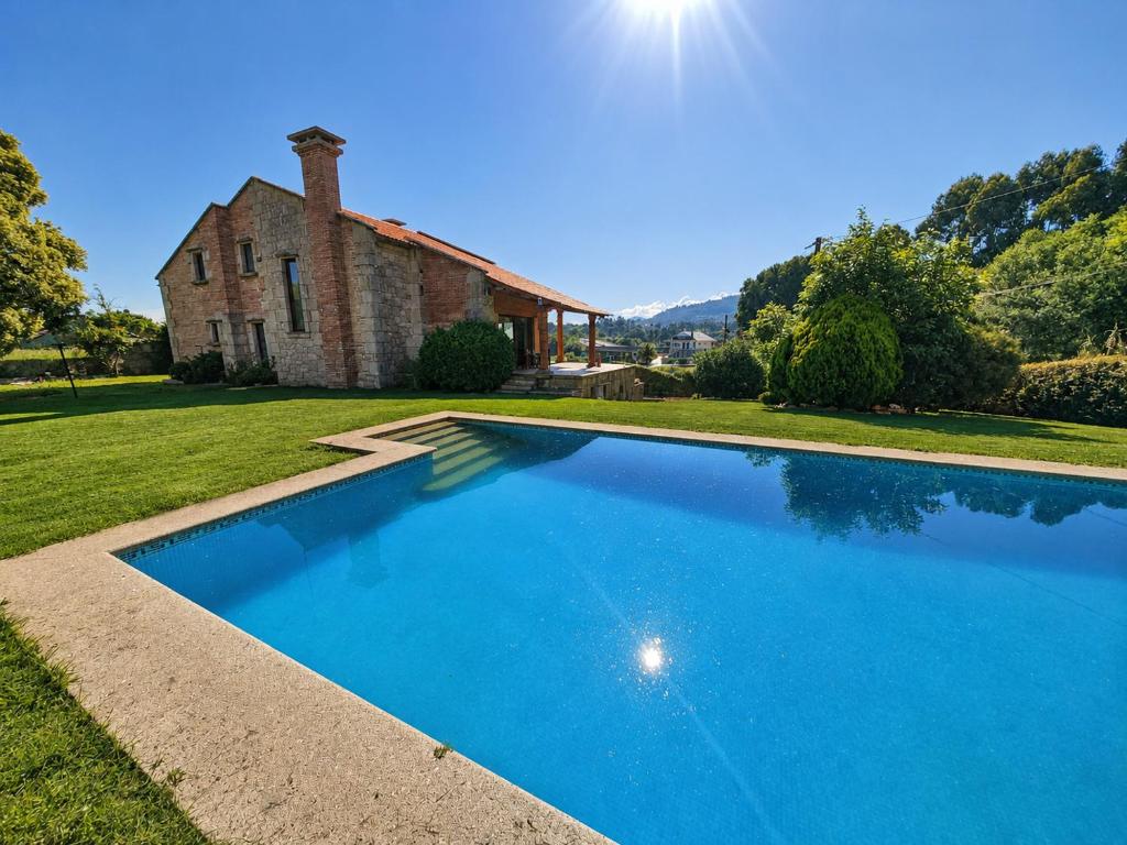 a large blue swimming pool in front of a house at Vila Xocas in Baiona